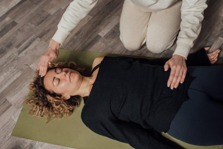 Ons team Therapeut voert Reiki behandeling uit met handen boven lichaam van cliënt op behandeltafel
